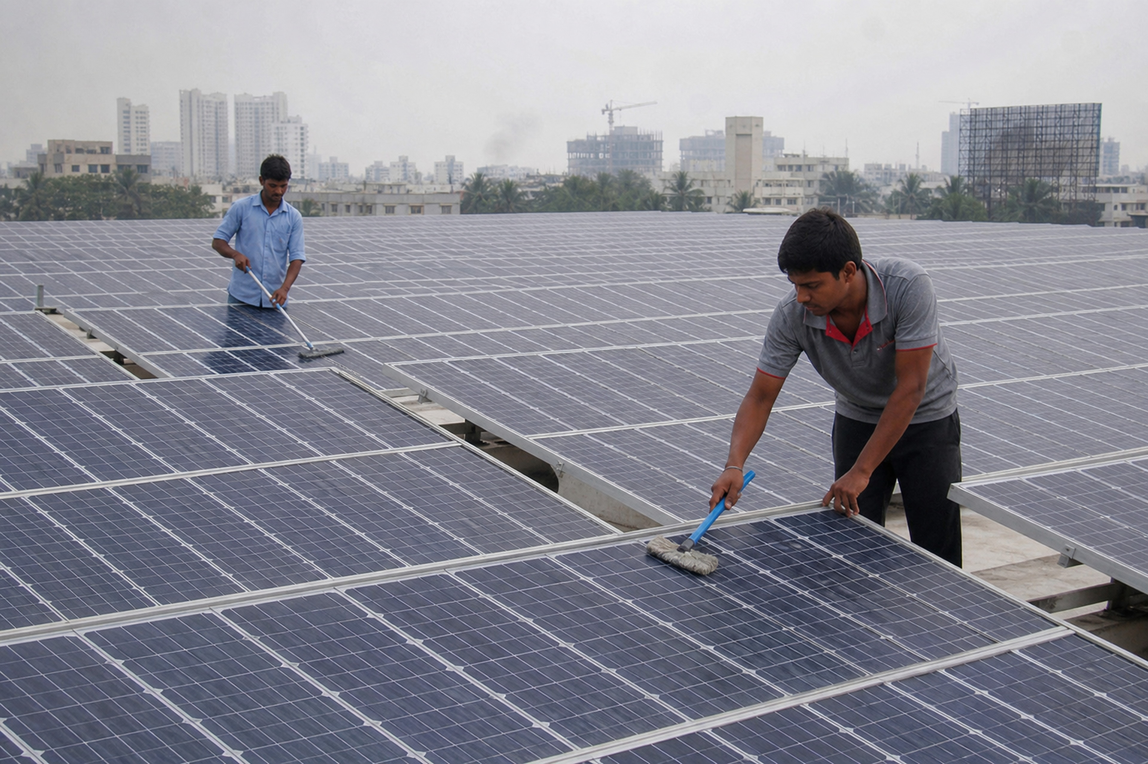 Indian technicians maintaining modules across a large rooftop array