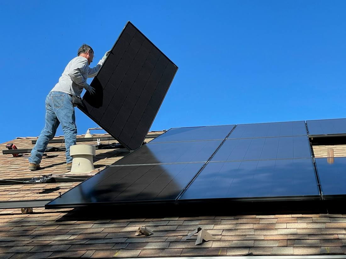 A solar technician securing modules during rooftop installation