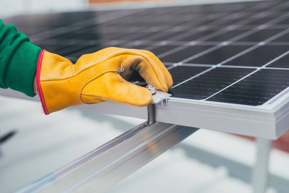 A gloved hand torquing a bolt on an aluminium mounting rail