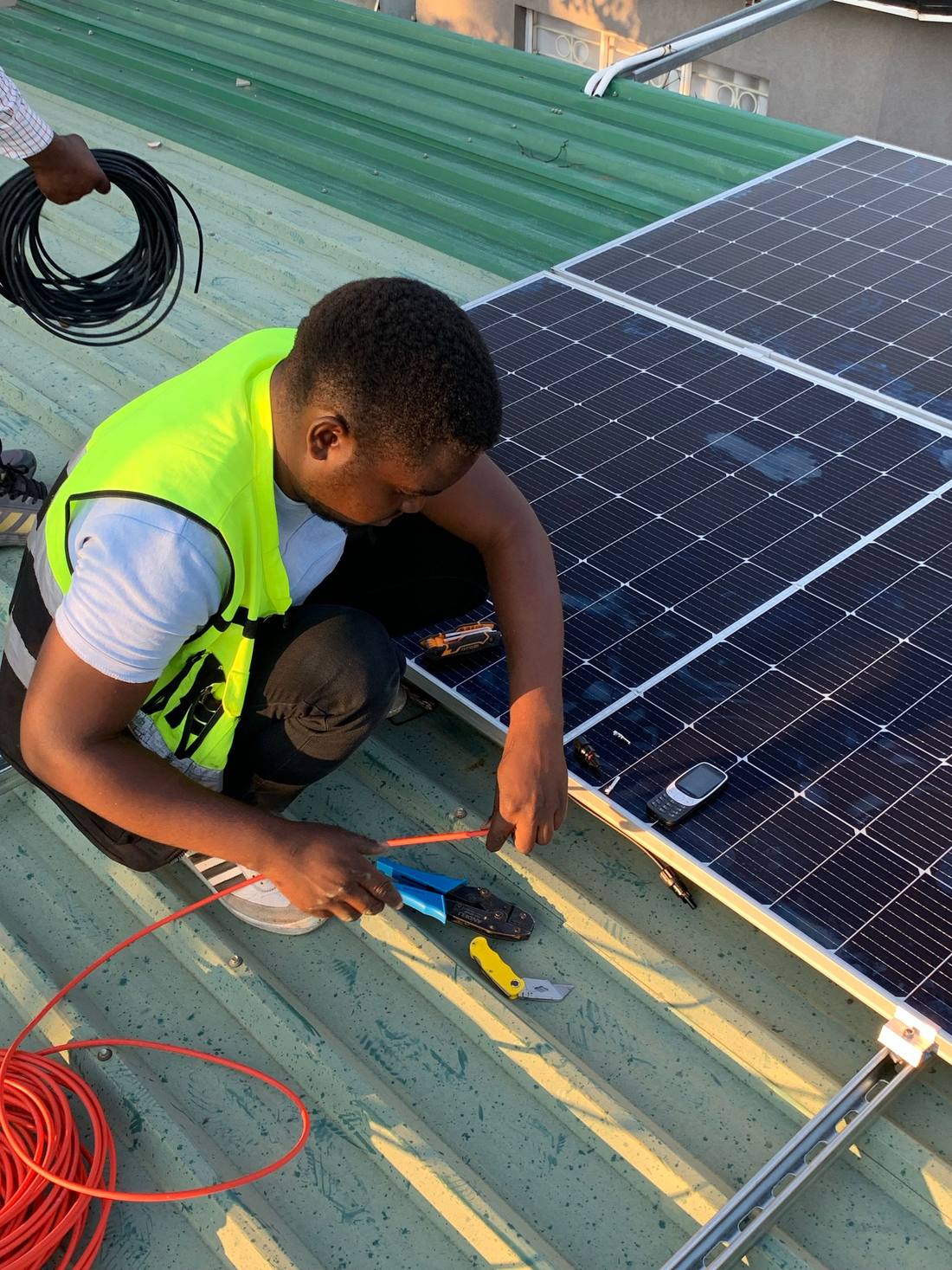 Technicians routing DC cabling during a rooftop solar installation