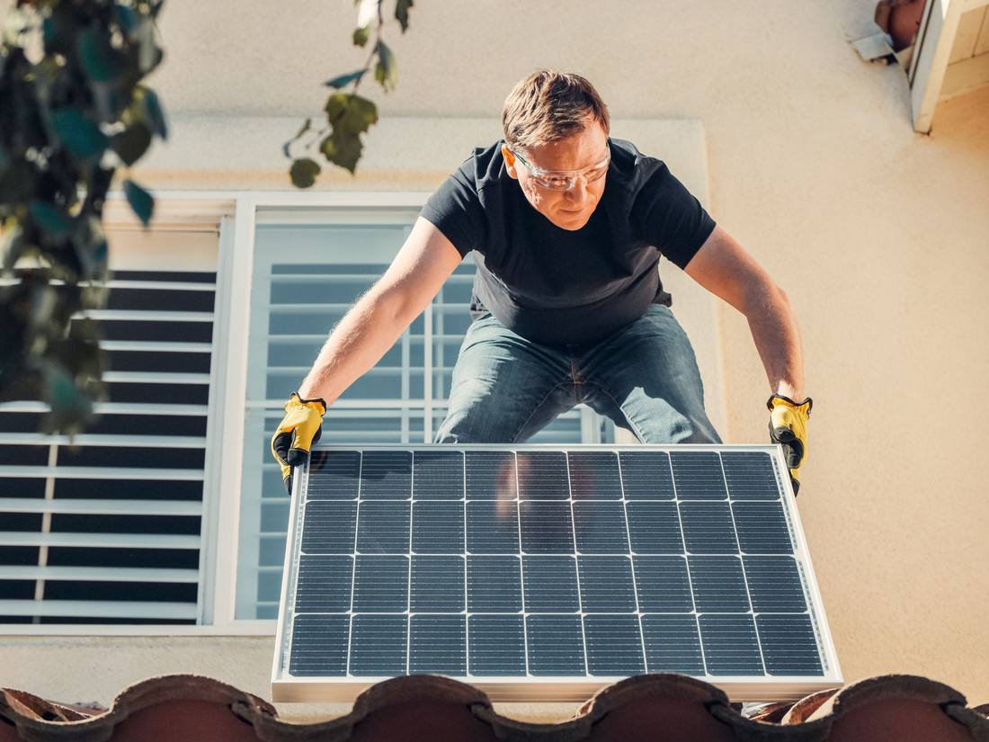 A technician carrying a solar module on site