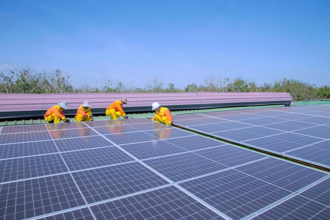 An installation crew mounting solar modules across a large rooftop